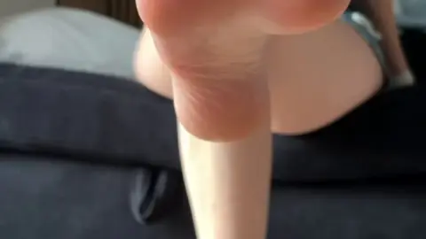 Slim brunette with red toenails shows off feet in bedroom