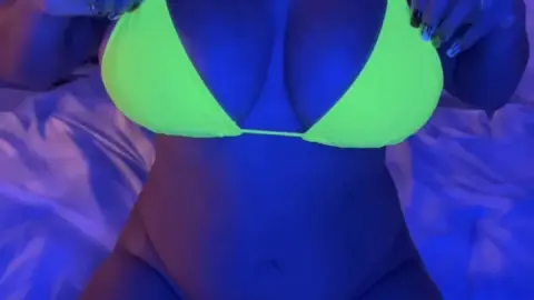 Latina with thick curly hair teases in blue-black lit bedroom