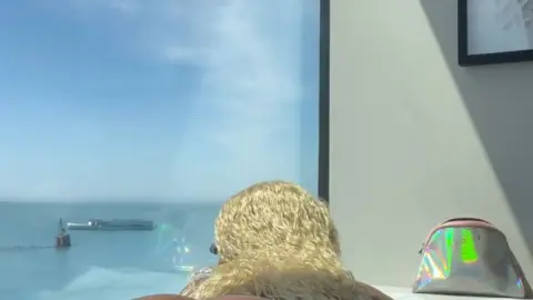 Black blonde curvy girl bending over on hotel bed, natural light