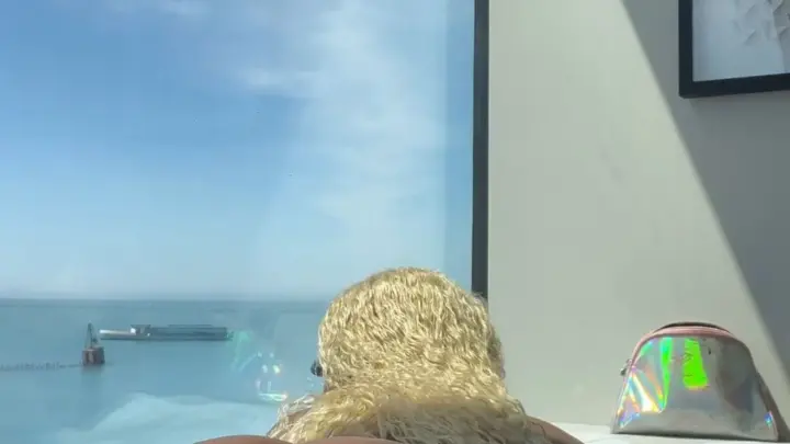 فتاة سوداء ممتلئة مع شعر أشقر مجعد ينحني على سرير الفندق