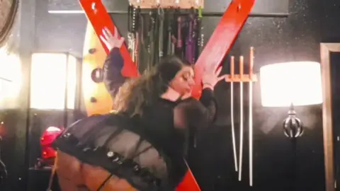 Mulher Curvilínea de 30 Anos Branca em Roupas Pretas e Meias de Rede Brinca com Vermelho