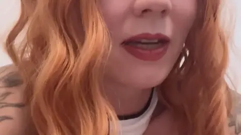 Redhead Asian girl with tattoos plays with toy in bedroom selfie