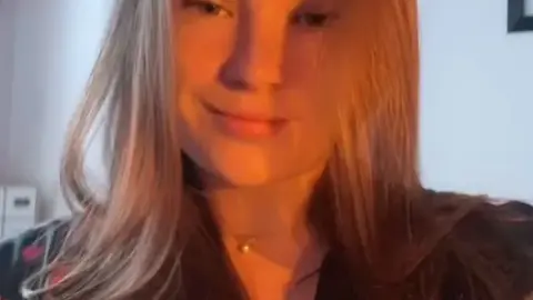 Blonde in heart-patterned shirt teases camera with soft smiles and shy