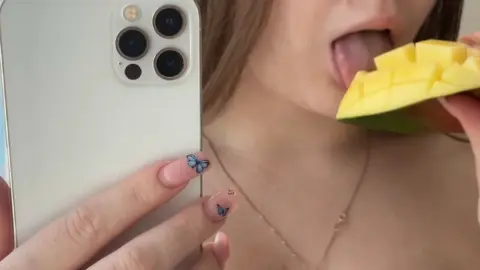 Брюнетка ест манго и делает селфи