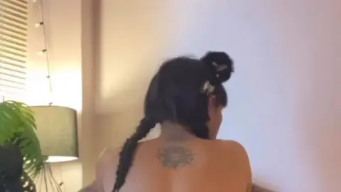 Black Woman in Snake Bodysuit Bends Over