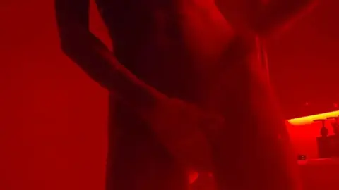 Nude brunette with dark braids and arm tattoos poses in bathroom