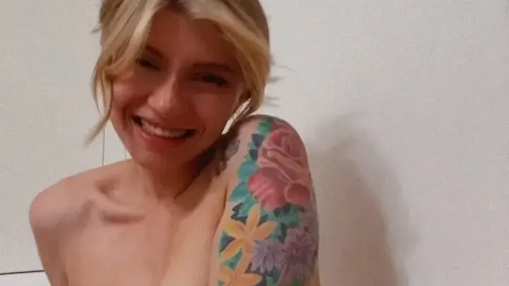 Blonde in badkuip, borsten bloot, lacht